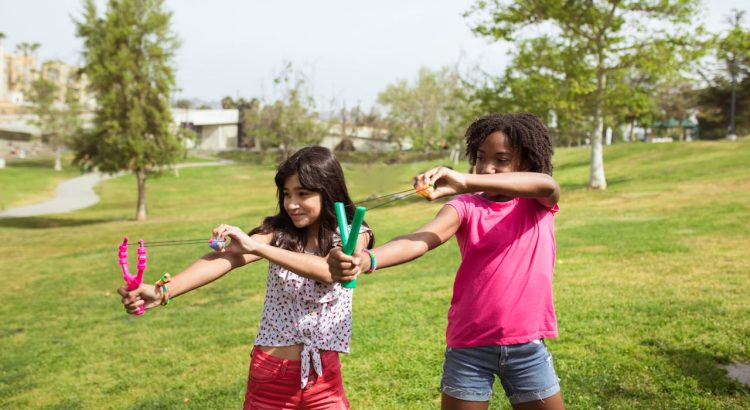 children using slingshots with ammo pouch setup during target practice outdoors